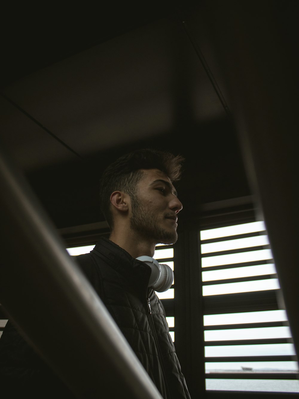 a man standing in front of a window with blinds