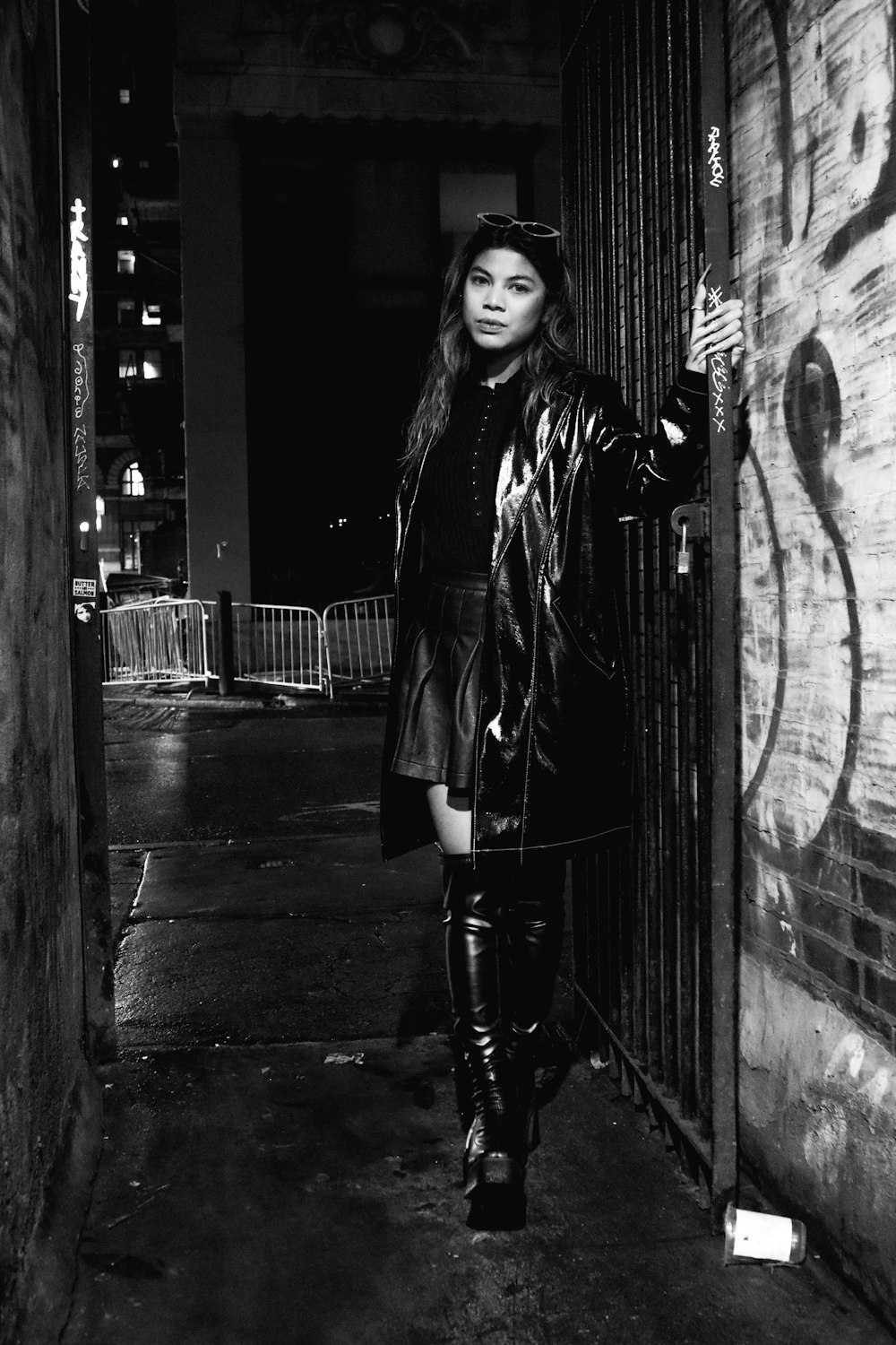 a woman in a leather jacket and boots standing in a doorway