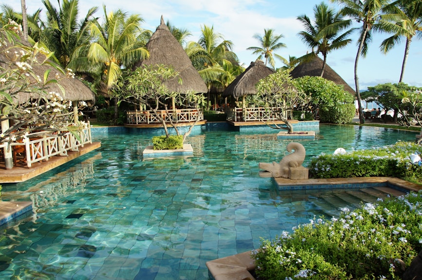 thatched cottages and a large pool with a statue in the middle of it