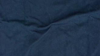 Close-up of dark blue textured fabric with subtle light reflections.