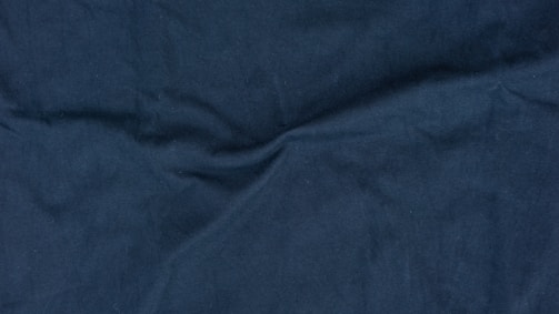 A dynamic shot of royal blue fabric being unrolled on a cutting table.