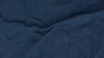 A close-up view of dark blue fabric with visible texture and folds.