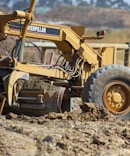 a yellow tractor is parked in the dirt