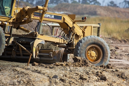 Photo of heavy machinery grading soil at a road construction site.