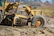 Heavy machinery grading a freshly dug driveway surrounded by green fields.