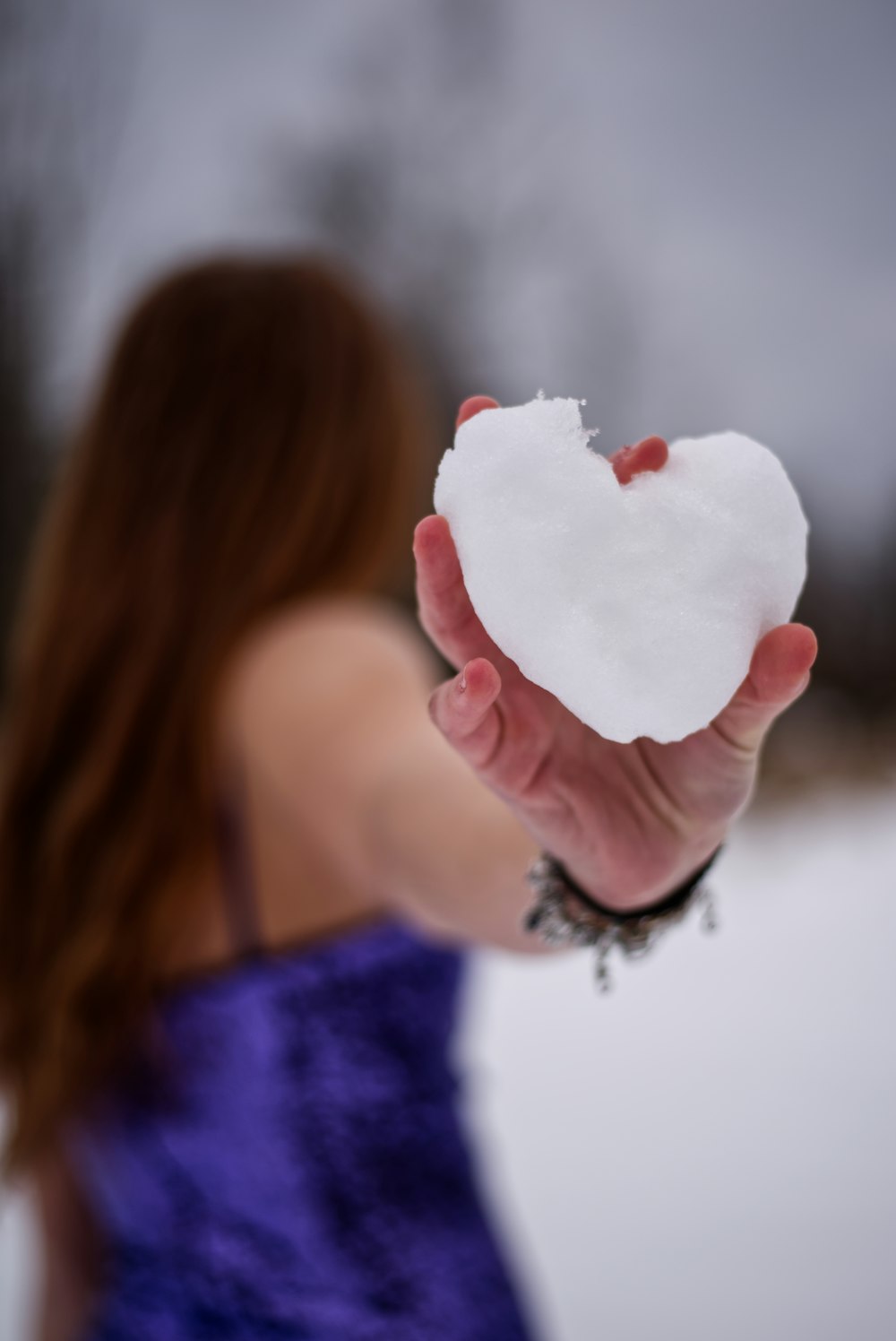 a woman in a purple dress holding a heart shaped piece of paper