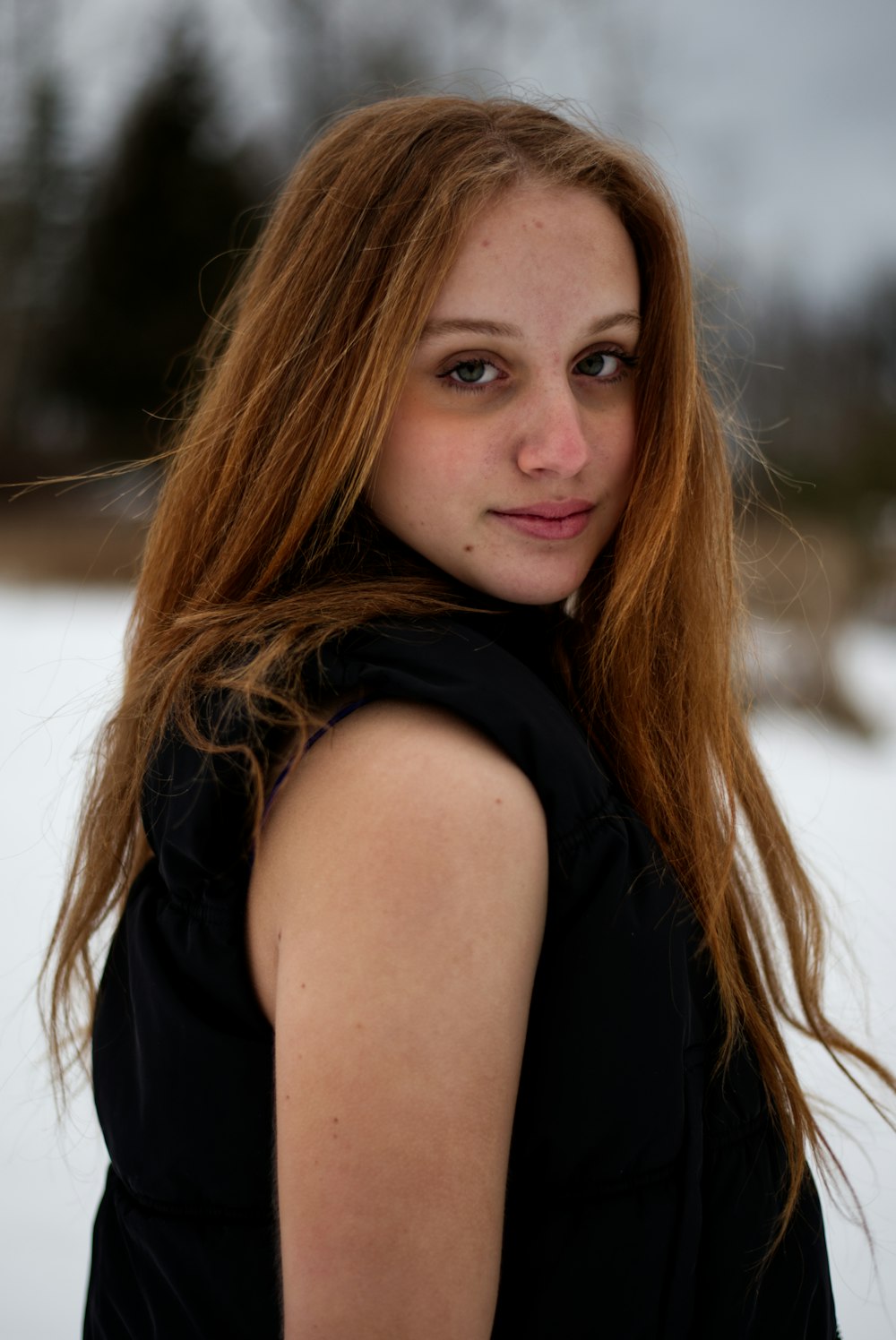 a woman with long red hair standing in the snow