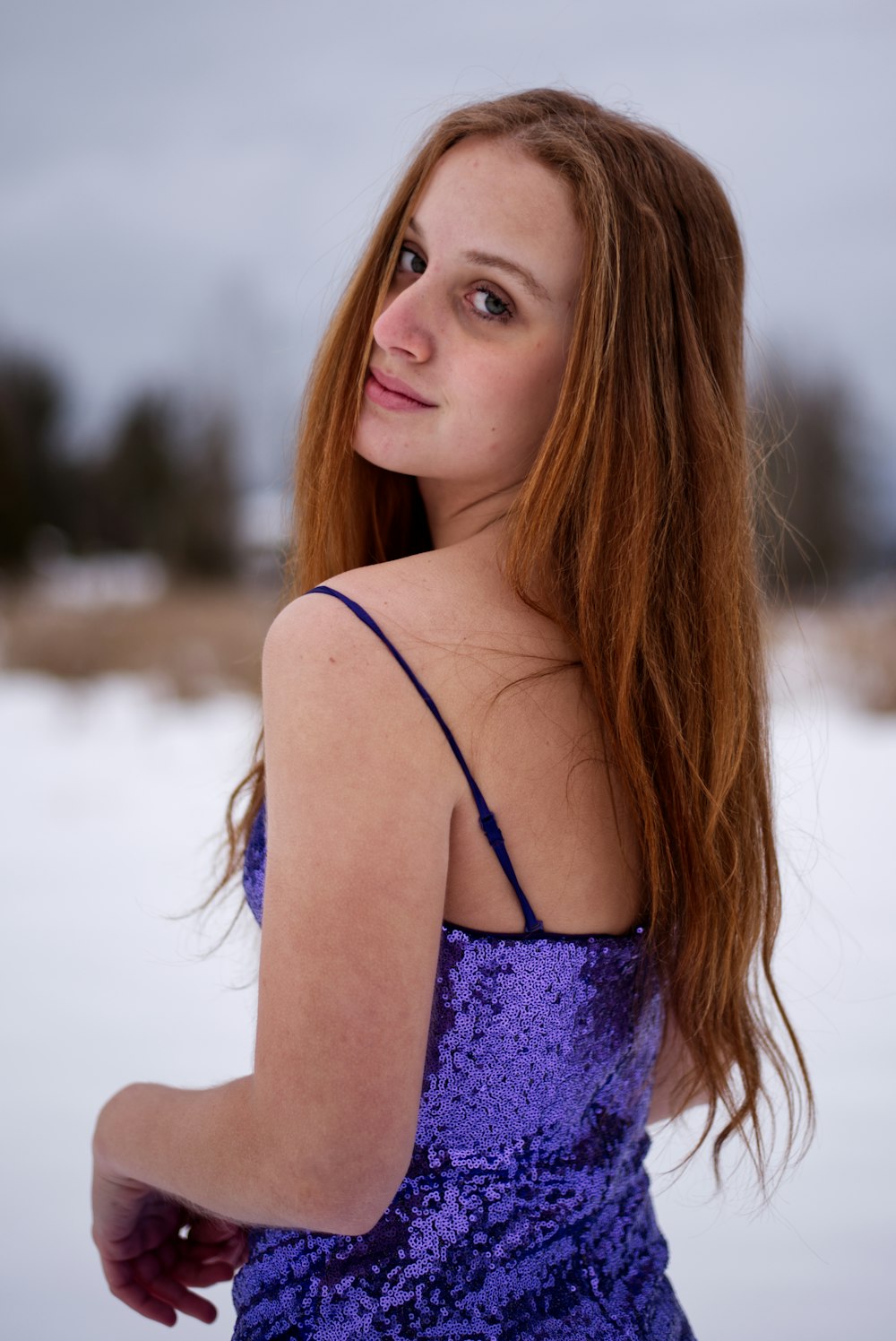 雪の中に立つ長い赤い髪の女性