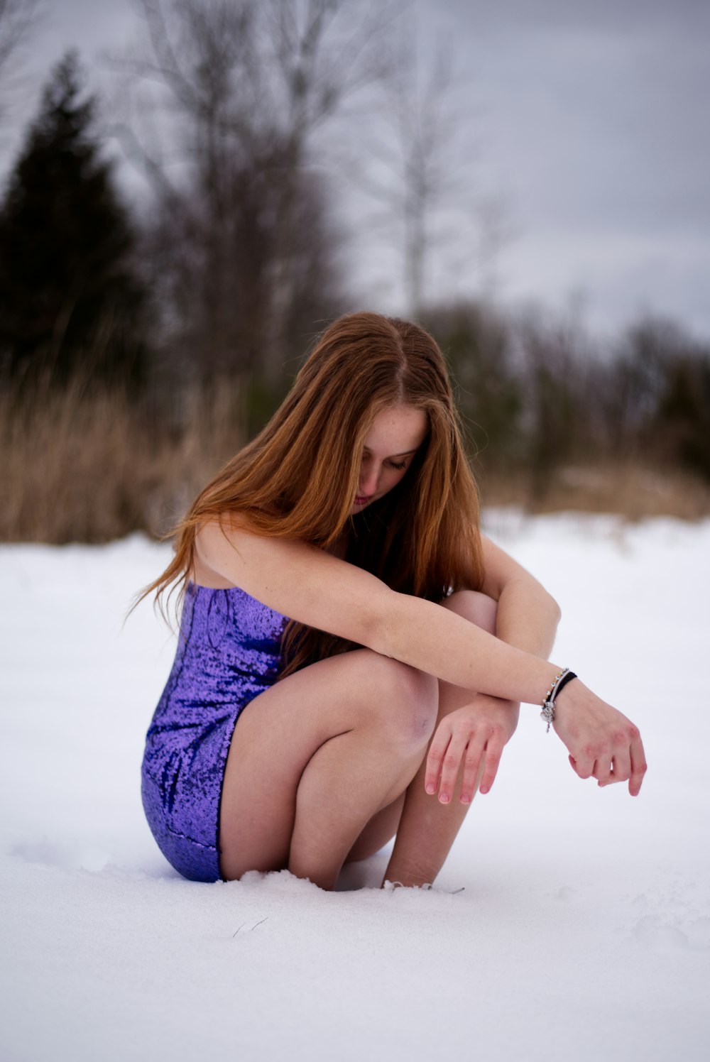 Una donna inginocchiata nella neve con le mani sulle ginocchia