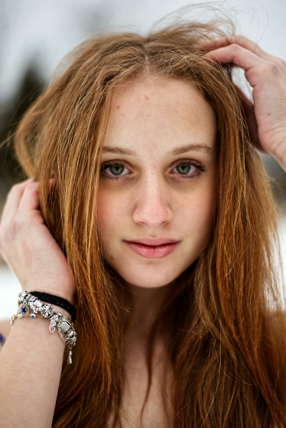 a woman with long red hair wearing a bracelet