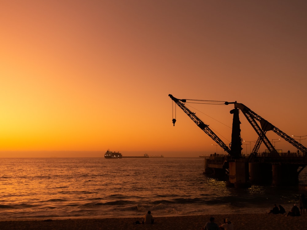 a large crane sitting on top of a beach next to the ocean