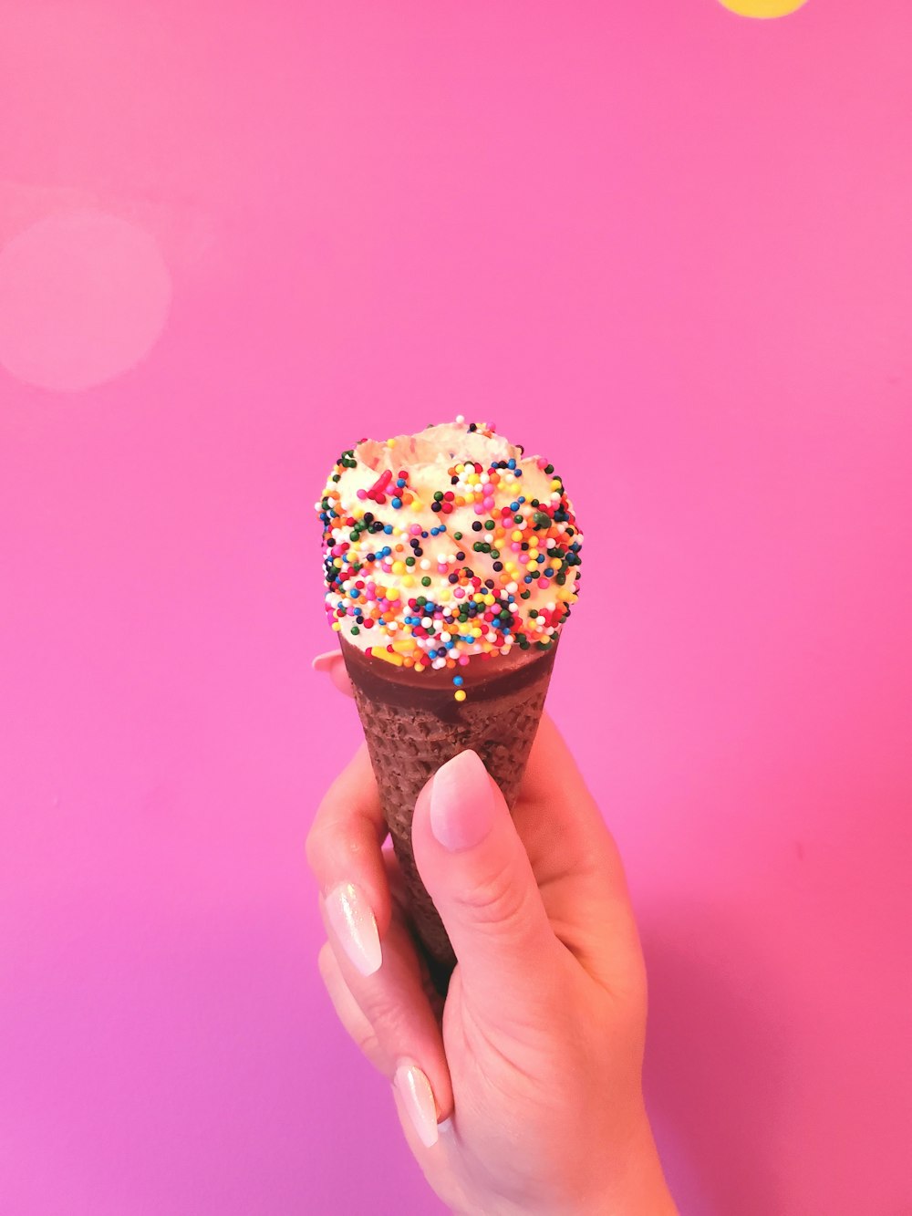 uma mão segurando um cone de sorvete com polvilhos