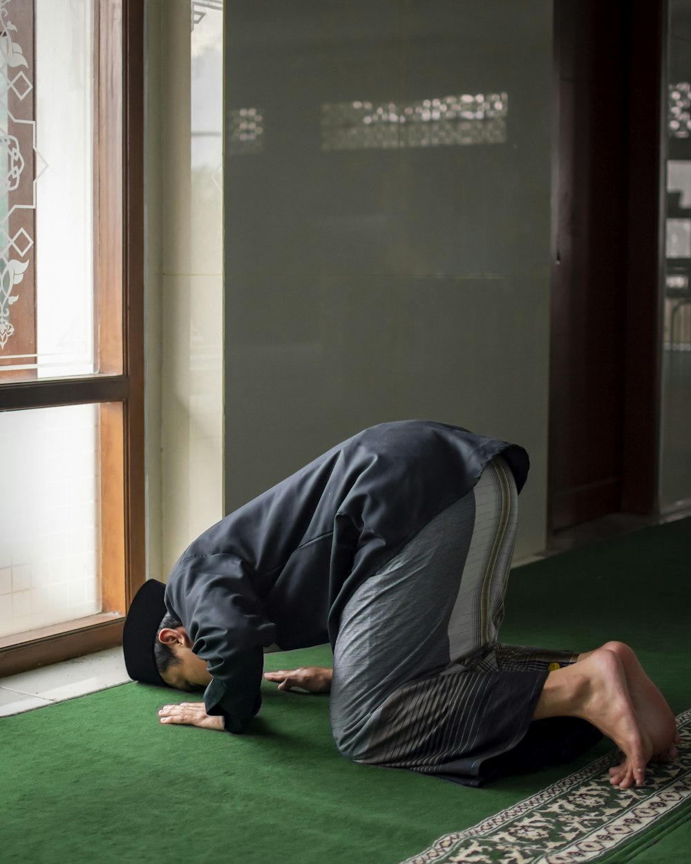 a man kneeling down on a rug in front of a window