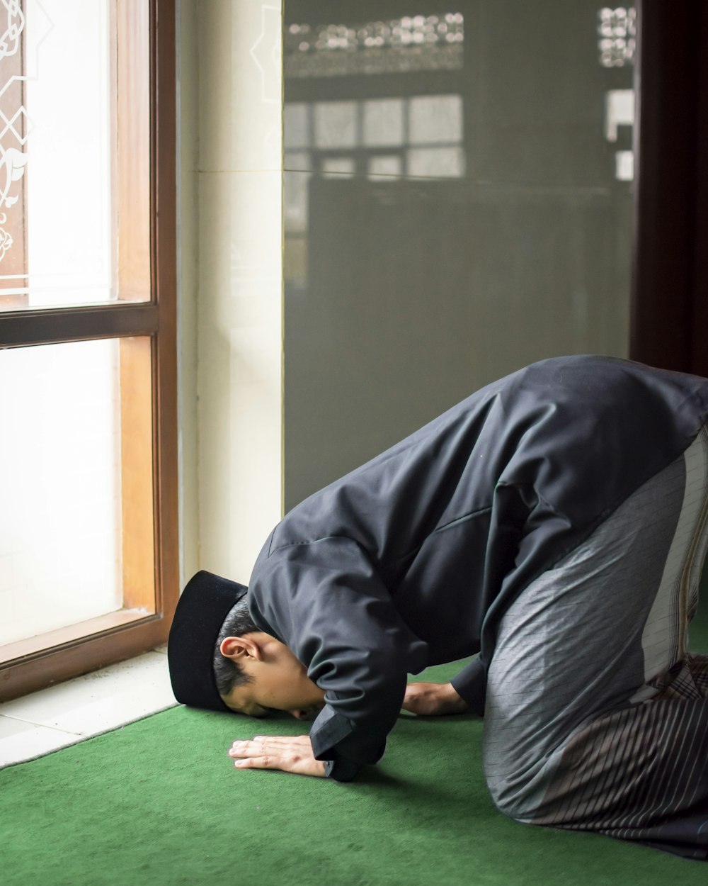 a man in a black suit is doing a handstand on a green carpet