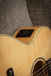 A close-up of an acoustic guitar resting on a wooden table.