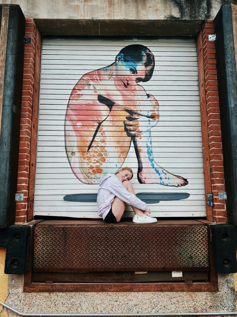 a woman sitting on a bench in front of a garage door