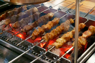 several skewers of meat cooking on a grill