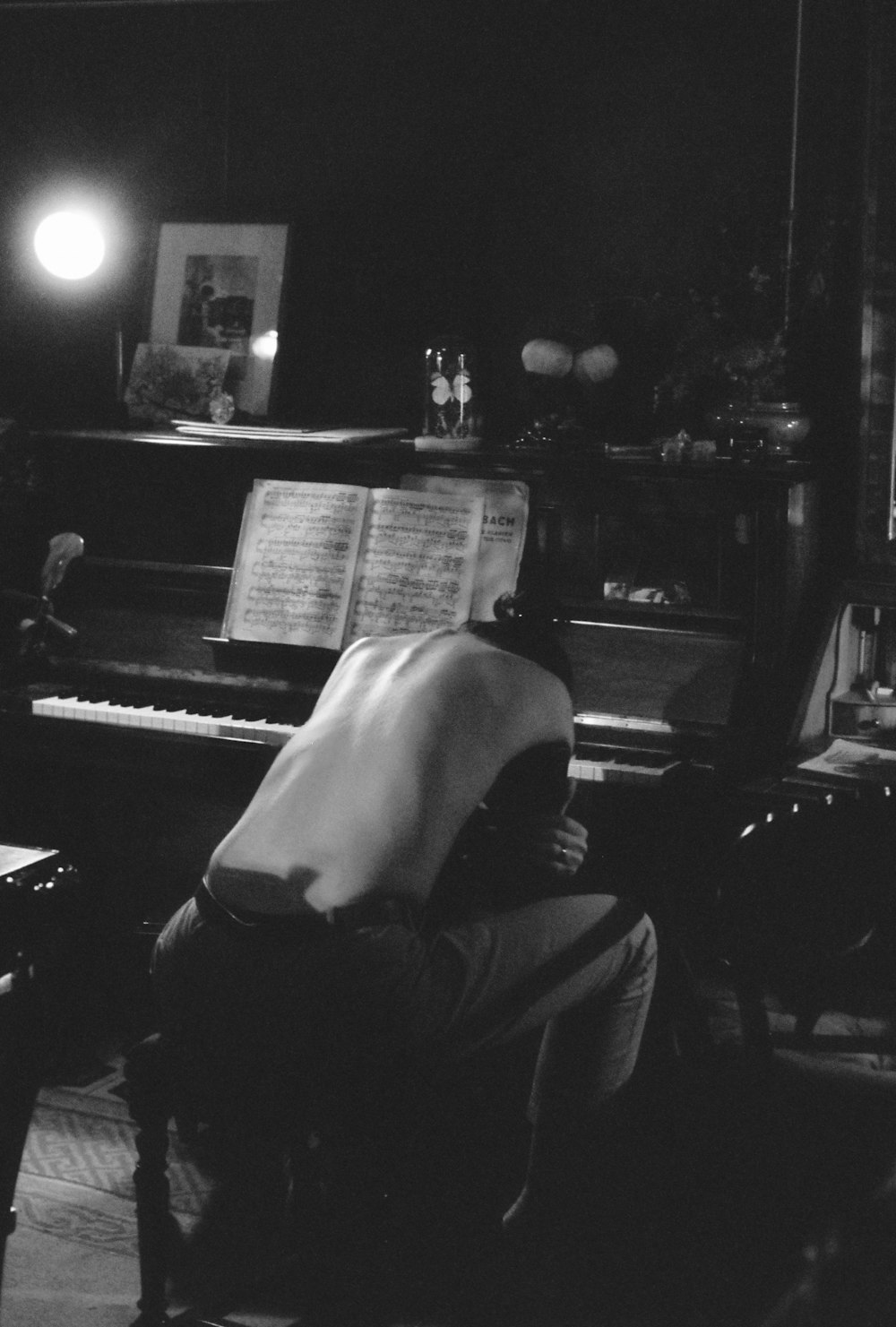 a man sitting in front of a piano in a dark room