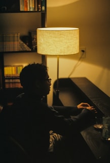 A cozy home setting with a person enjoying a glass of water beside a window with soft morning light and a stack of wellness books.