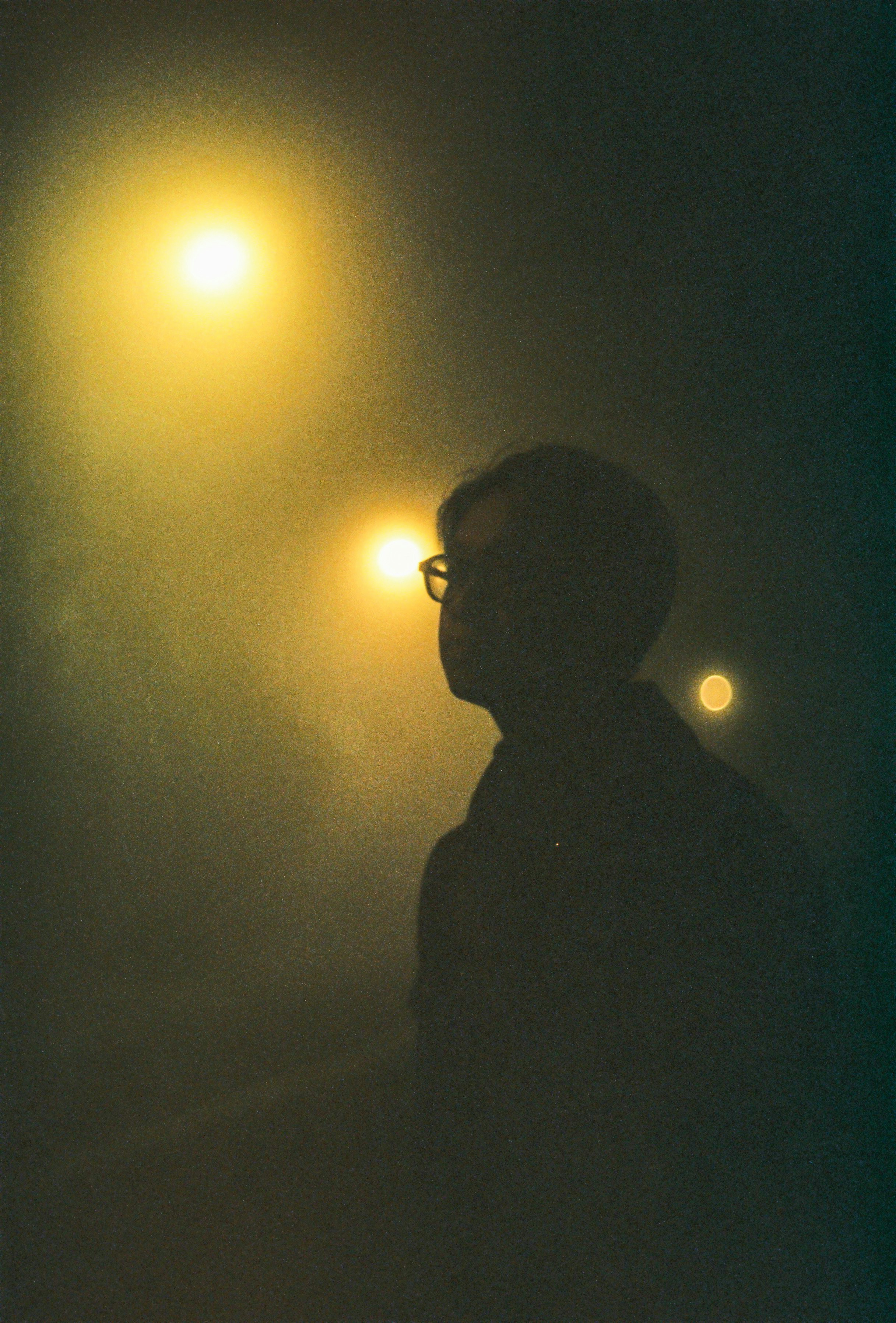 a man standing under a street light in the fog