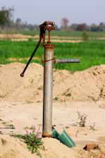 a pipe sticking out of the sand with a green field in the background