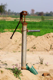 a pipe sticking out of the sand with a green field in the background