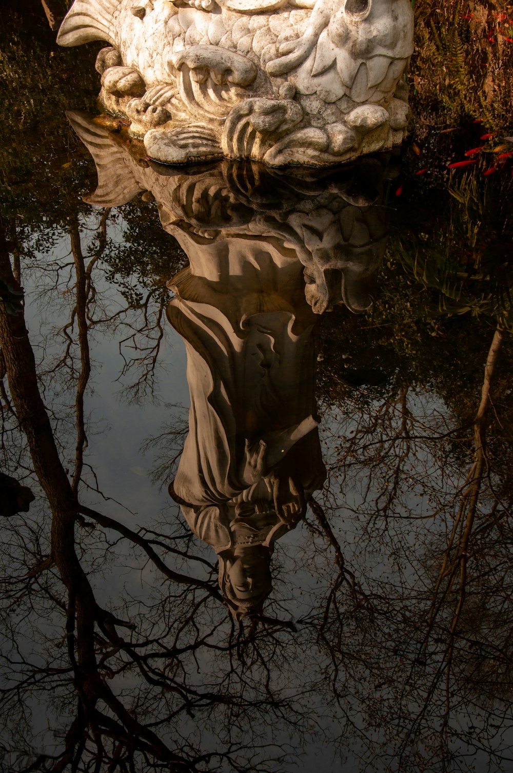 a reflection of a statue in a body of water