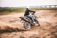 A rider performing a stunt on a dirt bike in an open field.