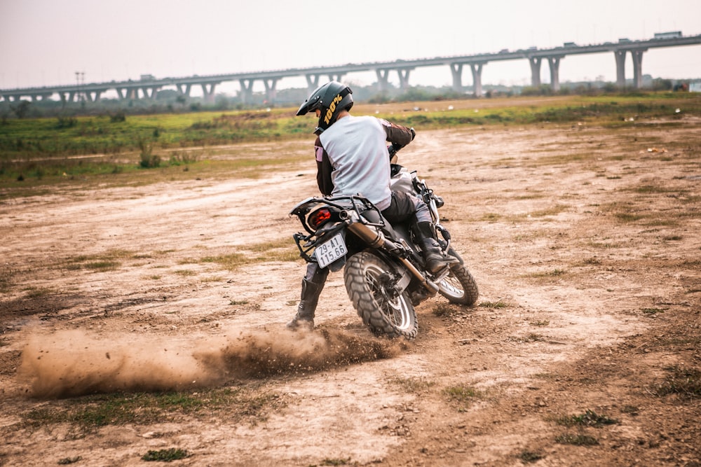 Un homme conduisant une moto hors route au sommet d’un champ de terre
