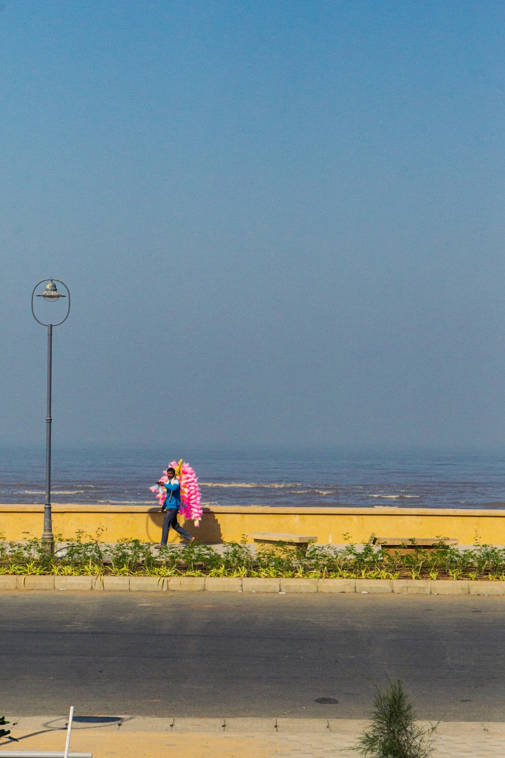 a couple of people walking down a street next to the ocean