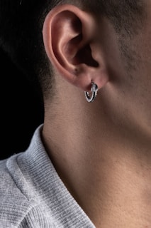 A delicate ear piercing with a small, elegant silver hoop in a cozy studio setting.