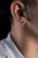 Close-up of a delicate titanium piercing jewelry on a person's ear with a soft natural background.