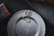 A set of matte black and copper toned minimalist jewelry displayed on a vintage wooden table