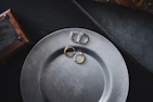 A set of matte black and copper toned minimalist jewelry displayed on a vintage wooden table