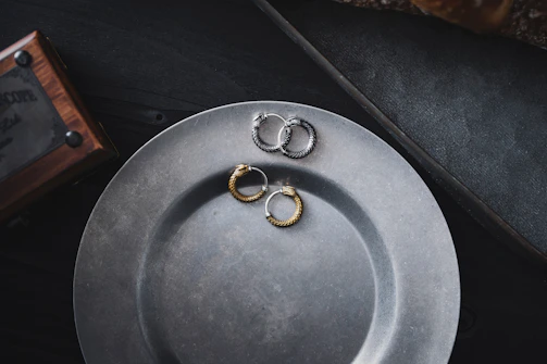 Minimalist shot of a pair of oxidized silver earrings with a matte finish, placed on a white marble slab.