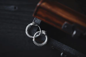 A pair of handcrafted silver earrings resting on a rustic wooden surface
