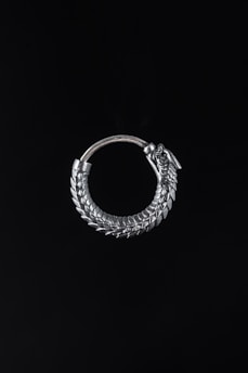 A spiked earring crafted from polished chrome, gently bobbing in zero gravity on a black void backdrop.