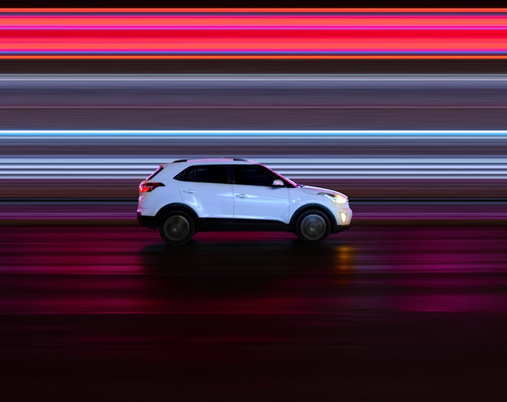 a white car driving down a street at night