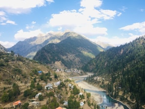 A scenic mountain landscape with lush green valleys and a winding river.