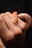 A close-up of a hand gently holding a small orange and white snake. The snake's scales have a distinct pattern, and its head is prominently visible with focused eyes.