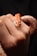 A close-up of a hand gently holding a small orange and white snake. The snake's scales have a distinct pattern, and its head is prominently visible with focused eyes.