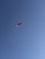 A lone paraglider with a red canopy soars against a clear blue sky, creating a sense of freedom and adventure.