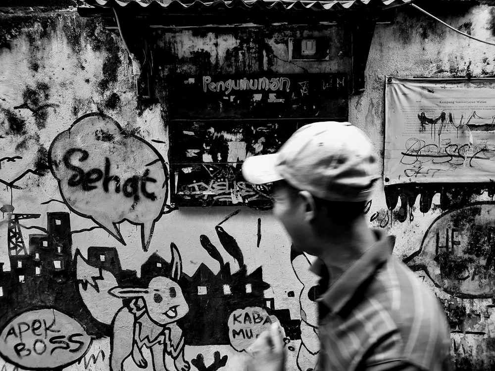 a man walking past a wall covered in graffiti