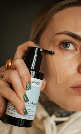 Person gently cleansing face with foam cleanser in a bright bathroom