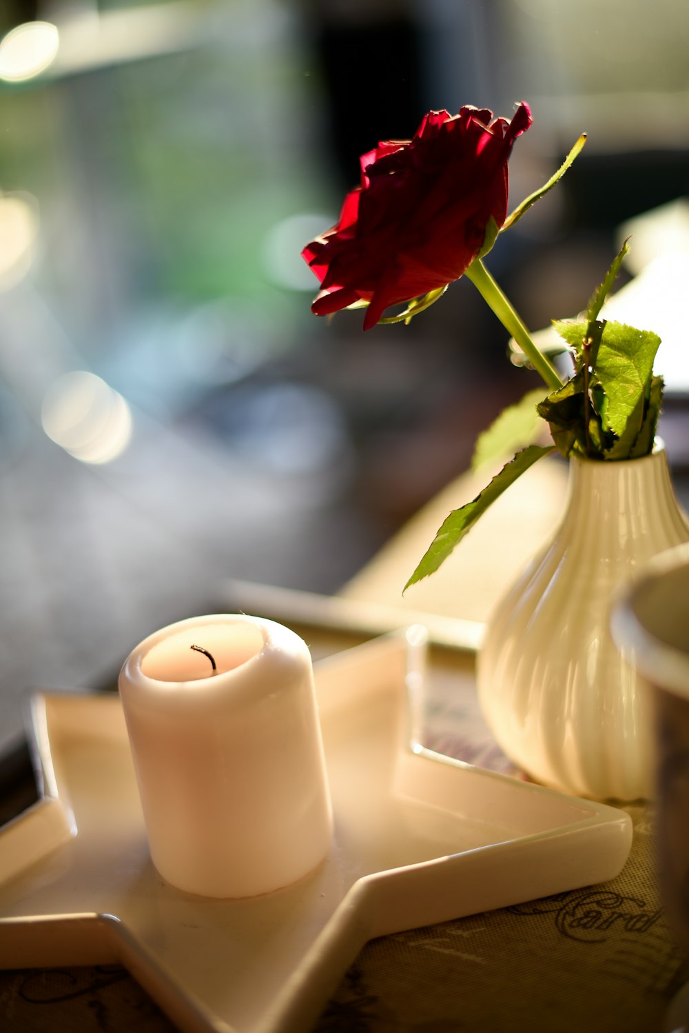 a single red rose sits in a white vase