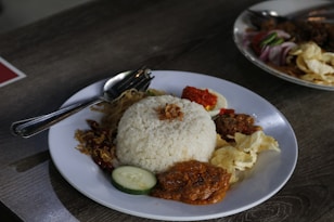 a white plate topped with rice and meat