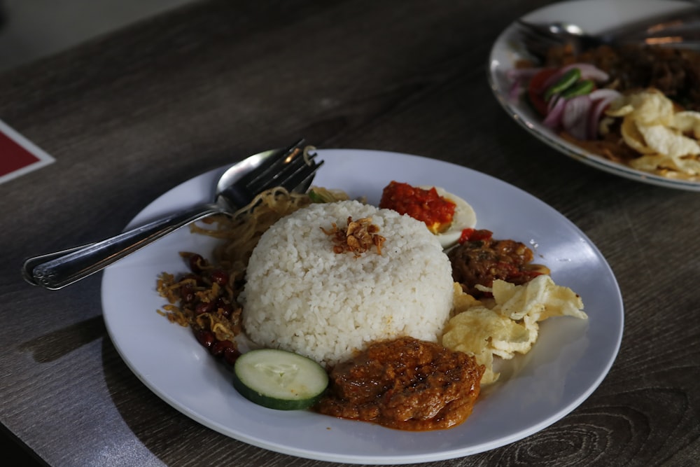 un plato blanco cubierto con arroz y carne