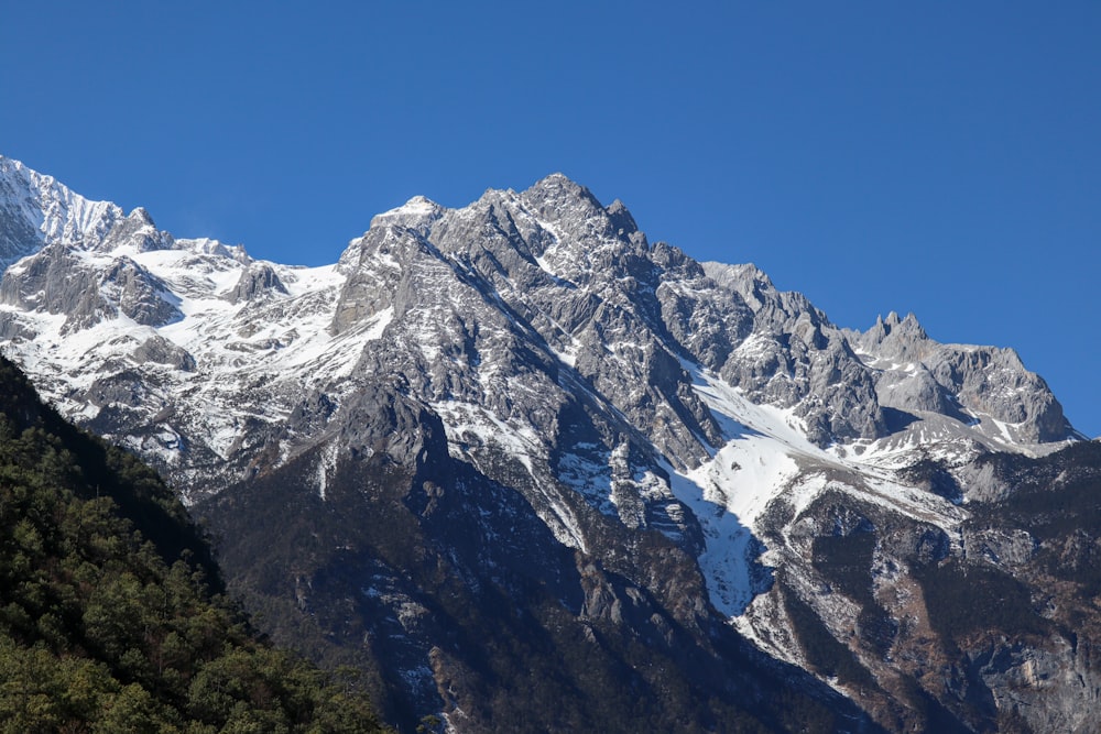 a large mountain covered in snow under a blue sky