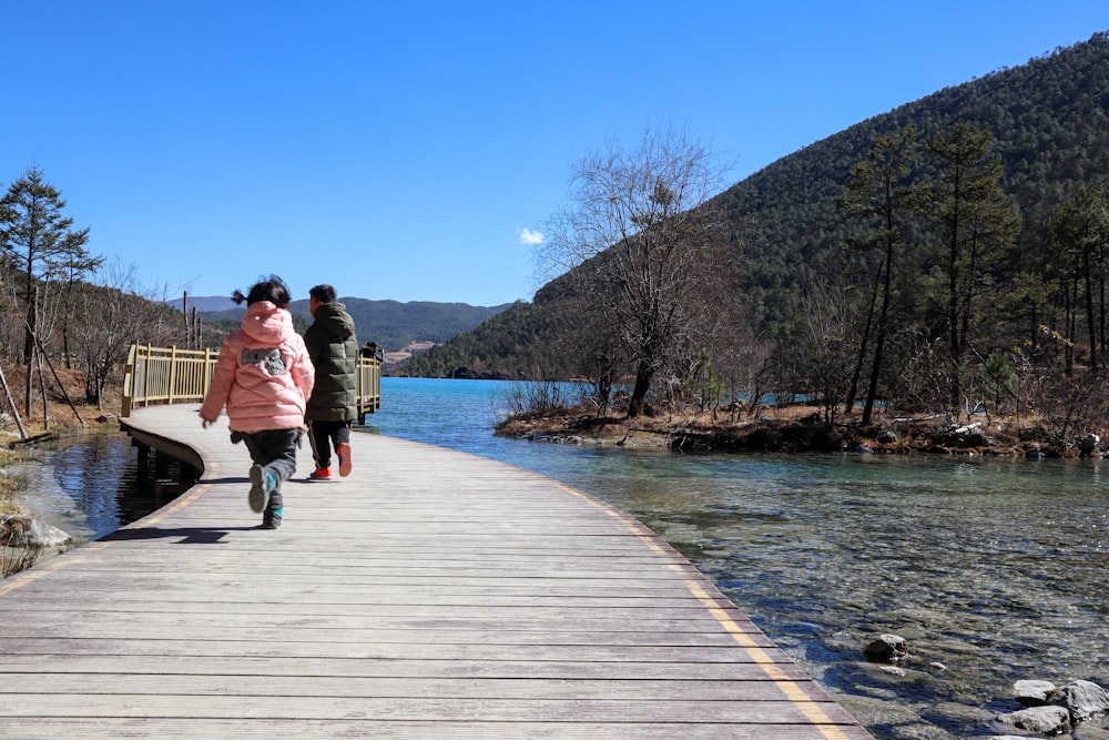 a couple of people walking across a wooden bridge