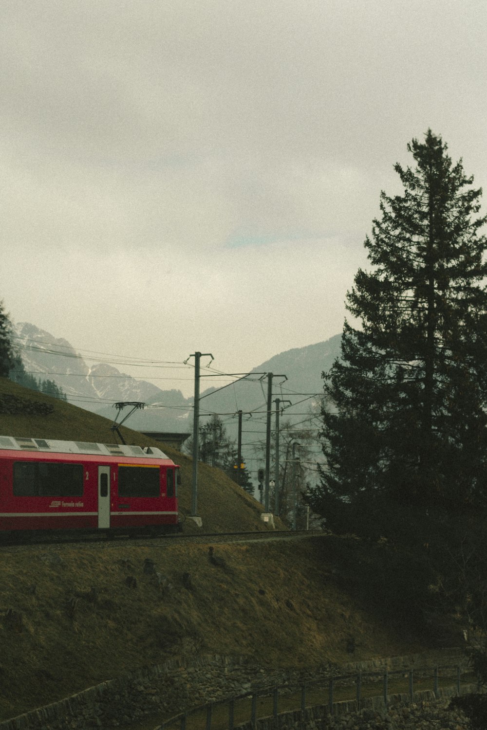 a red train traveling down train tracks next to a forest